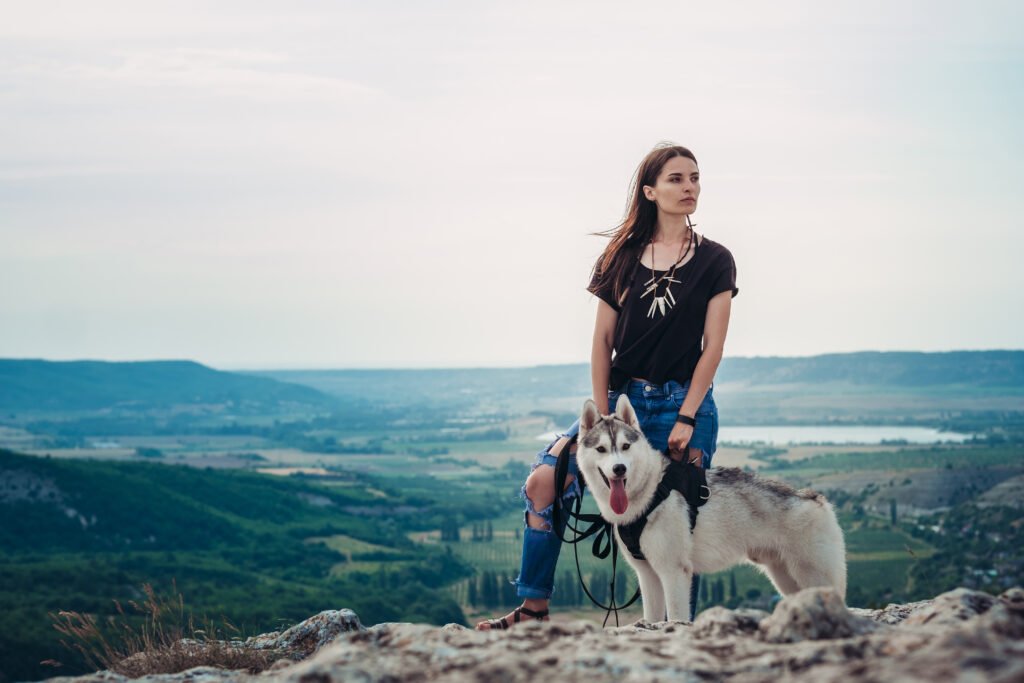 woman hiking with husky on a mountain